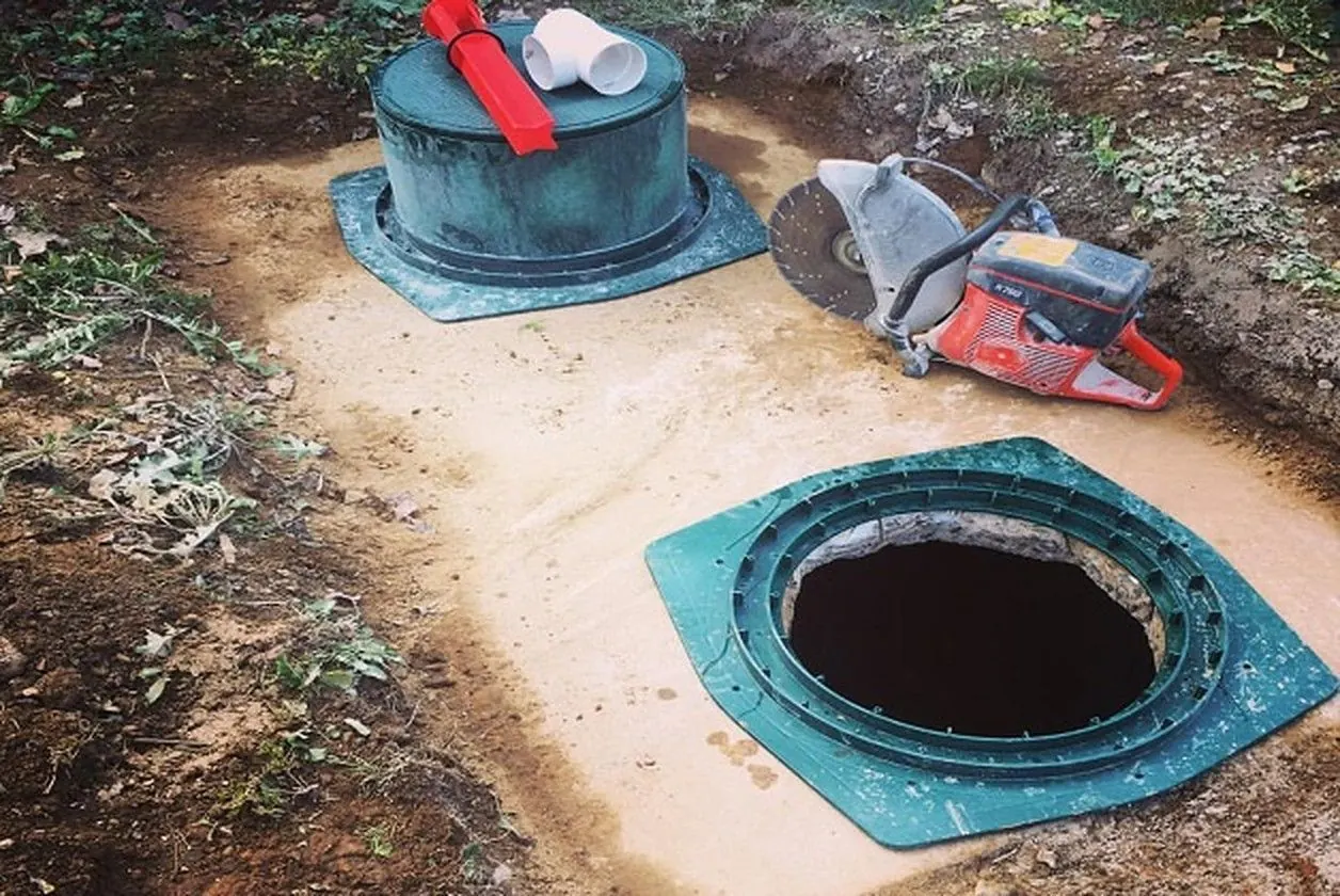 Septic tank riser installation: a finished green riser with lid beside an open tank access with its riser adapter ring in place